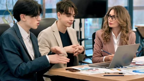 Business meeting in an office, female team leader and two young workers discussing business affairs
