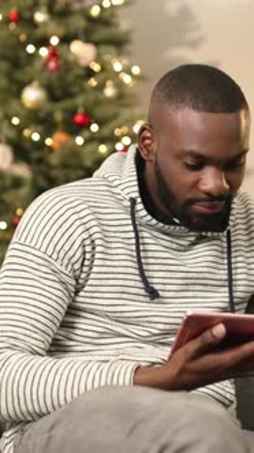 NEW YORK December13 2017 African Man with Beard in Informally Clothes Sitting on Couch with Colored