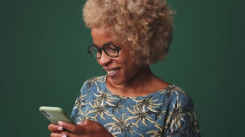 Close up, smiling woman holds mobile phone in her hands answers message, isolated on blue background