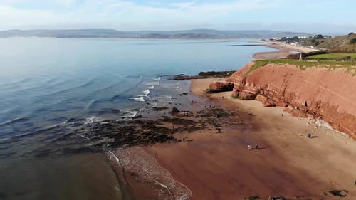 Aerial Of Orcombe Beach And Cliff Coastline In Exmouth With Visitors On Beach On Sunny Day. Dolly Fo