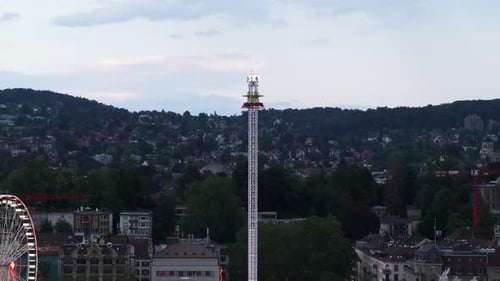 Aerial Slide and Pan Shot of Tall Tower Scaring Attraction in Amusement Park Colour Neon Lights