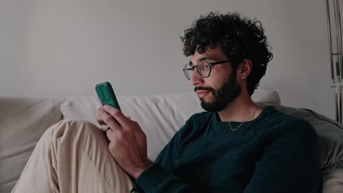 Man Relaxing on Couch Using Smartphone
