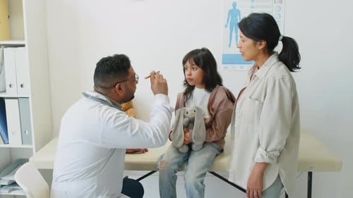 Doctor Checking Young Girl's Throat with Mother Present