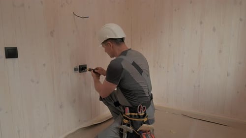 Electrician Installing Electrical Outlet in New Home Construction
