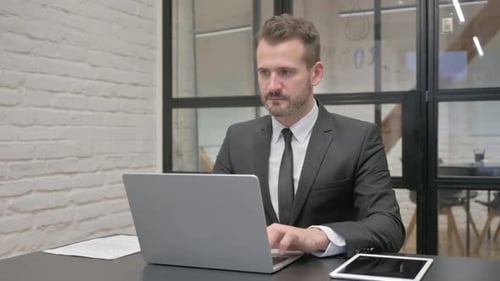 Focused Businessman Working on Laptop at Desk