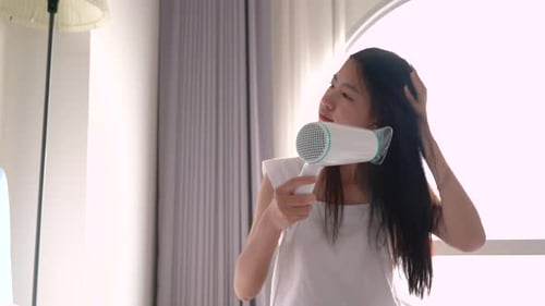 Young Woman Drying Hair in Bright Bedroom