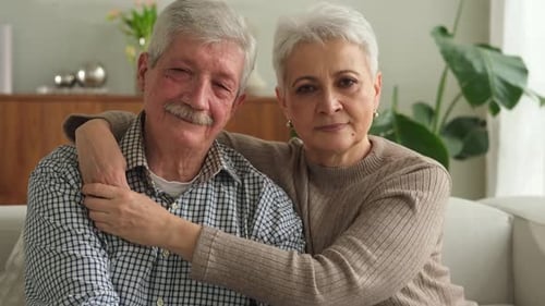 Senior Couple Embrace, Smiling Together on Sofa