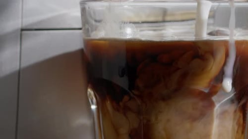 Cream Being Poured into a Glass of Iced Coffee