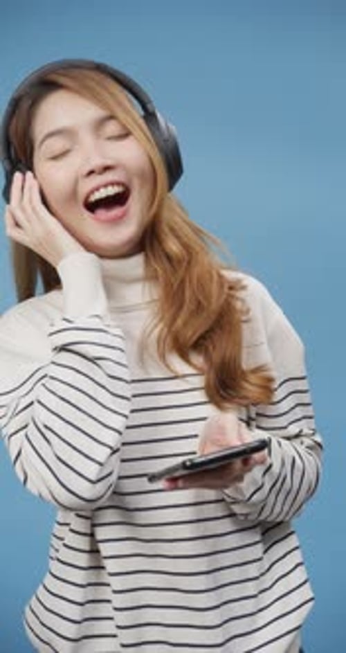Young Woman Dancing with Headphones and Smartphone