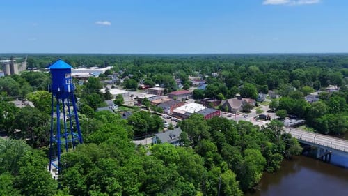 A blue water tower with "GRAND LEDGE" written on above green treetops in Michigan from above
