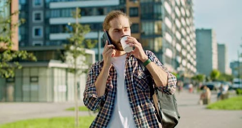Caucasian Handsome Man in Khaki Tshirt Having a Walk Outside in City Drinking Coffee and Talking on