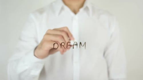 Man Writes Dream on Glass Surface in Studio