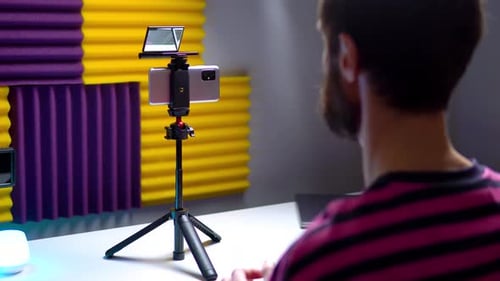 A Young Blogger Records a Video with Himself on His Phone in His Studio