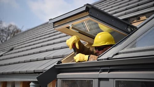 Worker Installing Skylight on House Roof