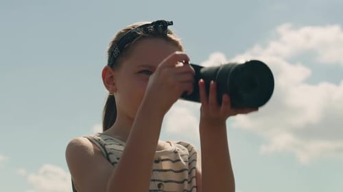 Girl with Camera Takes Pictures Outdoors on Sunny Day