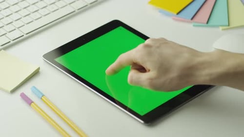 O designer está usando o tablet com tela verde no modo retrato.