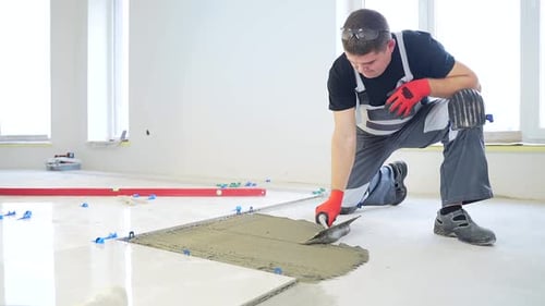 Man Applying Adhesive to Tile on Floor