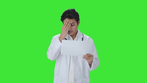 Tensed Indian doctor checking medical reports Green screen