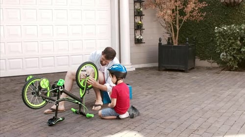 Father and Son Repairing Bicycle Outside Home