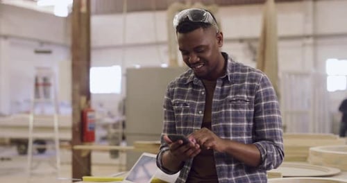 4k video footage about a young male woodworker using his smartphone in his workshop