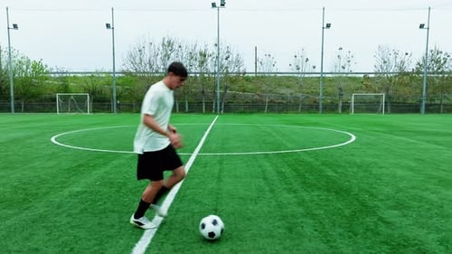 Un footballeur adolescent court seul avec un ballon sur le terrain