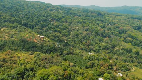 Lush green Costa Rican hills with scattered rural homes and winding dirt roads