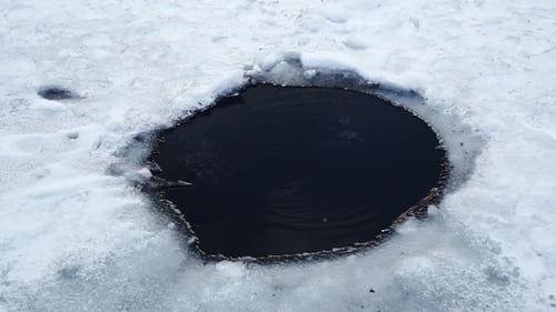 A small hole with bubbles rising to the surface in the frozen Tibble Fork reservoir lake for ice fis