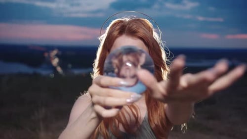 Auburn-haired Woman Holding a Crystal Ball at Sunset