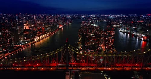 Approaching the Queensboro Bridge with red illumination. Lots of cars move by the bridge.