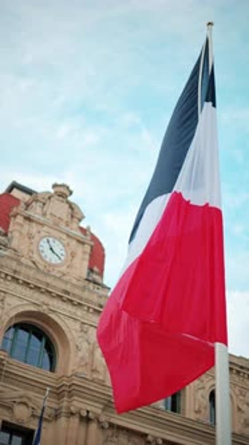 French flag waving in front of the Mairie de Cannes Town hall in Cannes, France. Vertical