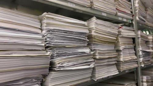 in a file archive there are shelves filled with stacks of paper
