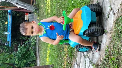 Little Boy Playing With Toy Tractor Outdoors