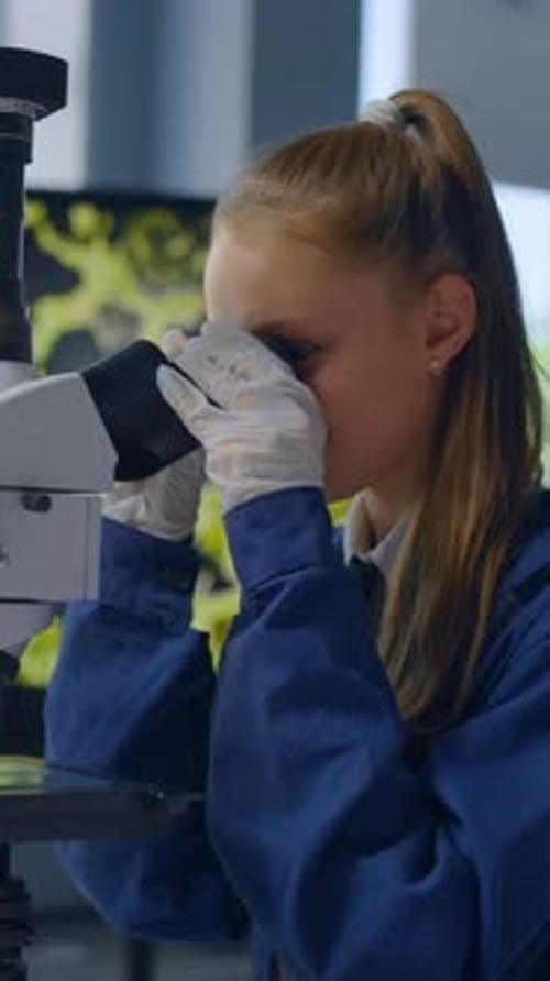 Young Woman Uses Microscope in a Lab