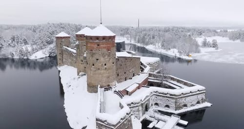 Aerial view circling the snowy Olavinlinna castle, winter in Savonlinna, Finland