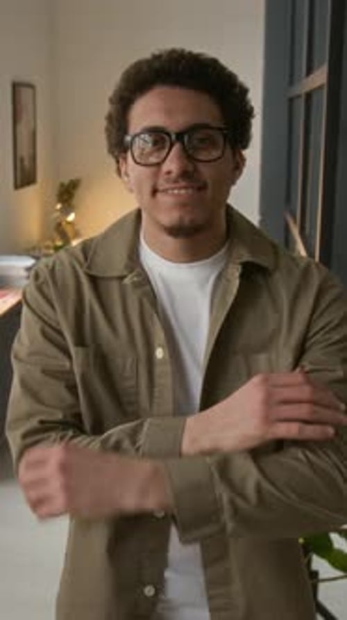 Portrait of Joyful Young Male Entrepreneur with Glasses Crossing Arms in Office