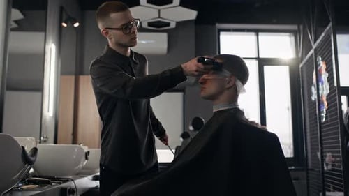 Junger Friseur benutzt elektrische Haarschneidemaschine und Kamm