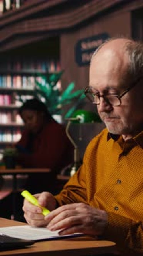 Vertical Video Elderly Student Using Highlighter Pen to Memorize Lesson Papers