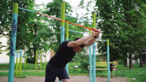 Middle Age Man Doing Strength Exercises with Resistance Bands Outdoors in Park