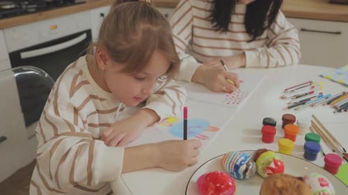 Child Drawing with Adult at Table at Home