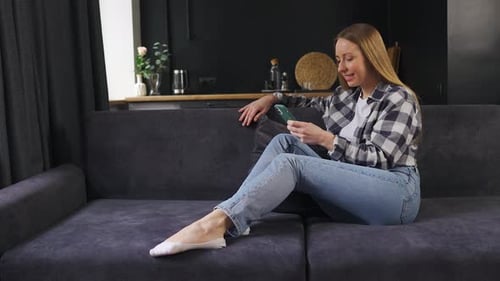 Woman Relaxing on Sofa Using Mobile Phone