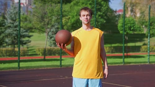 Young Man Holding Basketball on Outdoor Court