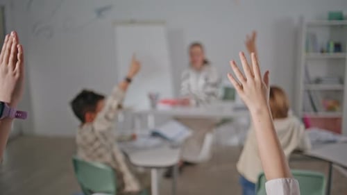 Unknown Kids Raising Hands Learning at School Closeup Blurred Woman Teacher