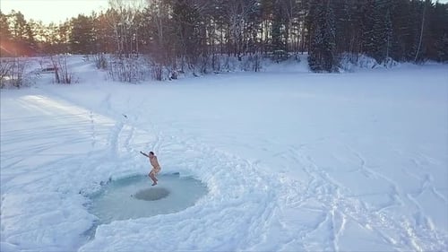 Man Swims in Icy Lake Ice Hole at Sunset