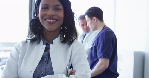 Smiling doctor with arms crossed at medical workplace