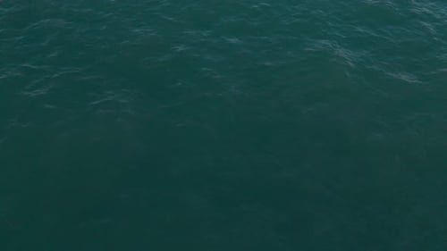 Olas del océano de un azul profundo capturadas desde arriba con reflejos de luz en la superficie
