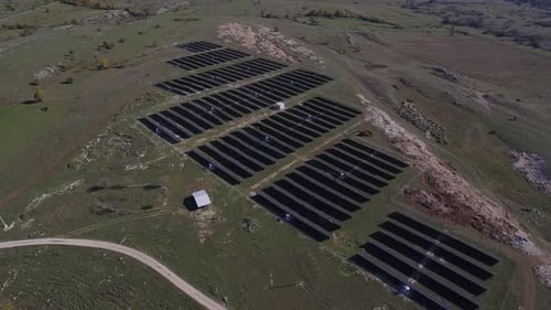 Solar Panel Array on Grassy Hillside - Aerial View
