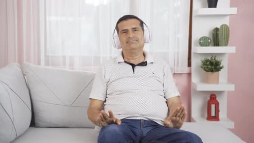Man Listening to Music with Headphones on Sofa