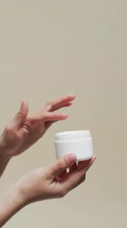 Woman Applies White Cream from Jar on Hands