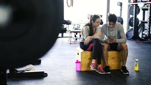 Fit Couple in Modern Crossfit Gym with Smartphone