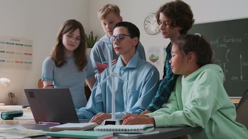 Students Gather around Teacher and Model Wind Turbine